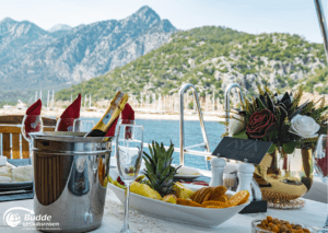 Tisch mit Sekt und Obst auf einer Yacht vor malerischer Bergkulisse