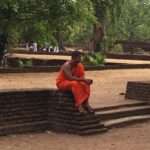 Ein buddhistischer Mönch sitzt nachdenklich vor einem Tempel in Sri Lanka