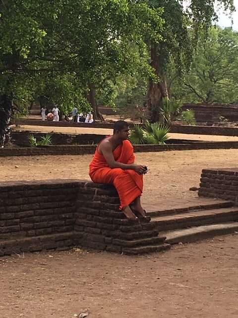 Ein buddhistischer Mönch sitzt nachdenklich vor einem Tempel in Sri Lanka