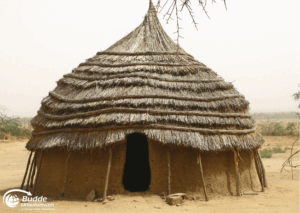 Kultur Urlaub Afrika: Traditionelles afrikanisches Lehmhaus mit einem runden Strohdach in einer ländlichen Umgebung.