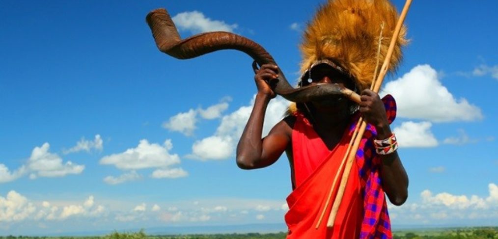 Massai-Krieger, der traditionelles Horn spielt. Afrika. Kenia. Masai Mara