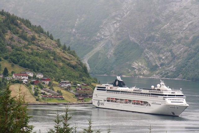 Norwegen-Kreuzfahrt-Geirangerfjord Das atemberaubende Bild zeigt den Geirangerfjord, einen der schönsten Fjorde in Norwegen, während einer unvergesslichen Kreuzfahrt. Das tiefblaue Wasser des Fjords wird von majestätischen Bergen umgeben, die in den Himmel ragen. Die steilen Felswände, üppigen grünen Wiesen und tosenden Wasserfälle verleihen dieser Landschaft eine unwirkliche Schönheit. Die Kreuzfahrt durch den Geirangerfjord ermöglicht es den Reisenden, diese beeindruckende Naturkulisse hautnah zu erleben und die Ruhe und Majestät der norwegischen Fjorde zu spüren. Tauchen Sie ein in diese spektakuläre Umgebung und lassen Sie sich von der beeindruckenden Schönheit des Geirangerfjords verzaubern.