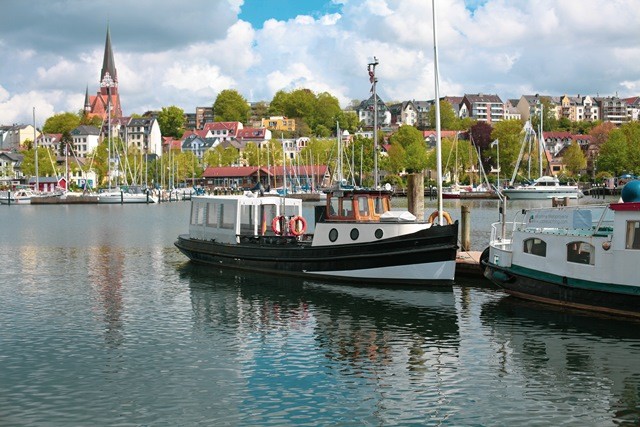 Barkasse Solitüde Schiff-Flensburg-Ostsee Ferienregion Das Bild zeigt die charmante Barkasse Solitüde, ein Schiff, das gemütliche Fahrten entlang der Ostseeküste in der Ferienregion Flensburg anbietet. Die Barkasse gleitet sanft über das ruhige Wasser und bietet den Passagieren eine entspannte Möglichkeit, die malerische Küstenlandschaft zu erkunden. Mit ihrem klassischen Design und ihrem freundlichen Personal ist die Solitüde ein beliebtes Schiff für Ausflüge und Entdeckungstouren. Auf dem Bild ist sie vor der Kulisse von Flensburg zu sehen, einer historischen Stadt, die für ihre maritimen Traditionen bekannt ist.