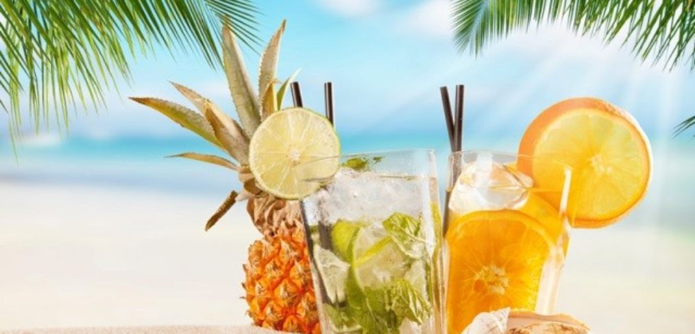 Cocktail-unter-Palmen-am-Sandstrand In diesem erfrischenden Bild ist ein köstlicher Cocktail auf einem Tisch unter schattenspendenden Palmen am Sandstrand zu sehen. Die glitzernde Sonne spiegelt sich im türkisfarbenen Wasser wider, während sanfte Wellen an den Strand rollen. Die exotische Atmosphäre lädt zum Entspannen und Genießen ein. Der Cocktail ist kunstvoll mit frischen Früchten und einem farbenfrohen Schirmchen garniert und verspricht einen Moment der Erfrischung und des puren Genusses. Dieses Bild erweckt das Verlangen nach einem tropischen Urlaub und erinnert uns daran, wie wunderbar es ist, sich an einem paradiesischen Ort zu entspannen.