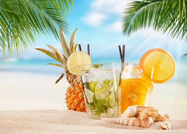 Cocktail-unter-Palmen-am-Sandstrand In diesem erfrischenden Bild ist ein köstlicher Cocktail auf einem Tisch unter schattenspendenden Palmen am Sandstrand zu sehen. Die glitzernde Sonne spiegelt sich im türkisfarbenen Wasser wider, während sanfte Wellen an den Strand rollen. Die exotische Atmosphäre lädt zum Entspannen und Genießen ein. Der Cocktail ist kunstvoll mit frischen Früchten und einem farbenfrohen Schirmchen garniert und verspricht einen Moment der Erfrischung und des puren Genusses. Dieses Bild erweckt das Verlangen nach einem tropischen Urlaub und erinnert uns daran, wie wunderbar es ist, sich an einem paradiesischen Ort zu entspannen.