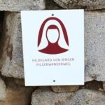 BU: Wegemarkierung Hildegard von Bingen Pilgerwanderweg; Copyright: Naheland-Touristik; Verwendungszweck: Das Bild ist unter Angabe des Fotonachweises Naheland-Touristik frei in Verbindung mit einem redaktionellen Beitrag zum Hildegard von Bingen Pilgerwanderweg in der Nahe.Urlaubsregion; weitere Verwendungen bedürfen der schriftlichen Zustimmung der Naheland-Touristik GmbH, www.naheland.net Auf diesem wunderbaren Bild sehen wir eine Wegemarkierung des Hildegard von Bingen Pilgerwanderwegs. Die deutlich erkennbare Markierung weist Pilgern den richtigen Weg auf dieser spirituellen Reise, die den Fußspuren der berühmten Mystikerin und Heilkundlerin Hildegard von Bingen folgt. Der Pilgerwanderweg bietet eine einzigartige Möglichkeit, die Schönheit der Natur zu genießen und sich gleichzeitig mit der spirituellen Lehre und dem Erbe von Hildegard von Bingen zu verbinden. Die Wegemarkierung lädt dazu ein, sich auf die Reise der Selbsterkenntnis und des inneren Wachstums zu begeben.