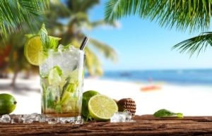 Karibik-Urlaub-Cocktail-am-Stand-Sandstrand-Palmen Ein paradiesisches Bild aus der Karibik! Hier sehen wir einen traumhaften Sandstrand, der von Palmen gesäumt ist. Ein entspannter Urlaub am Strand ist hier garantiert. Die Sonne strahlt vom blauen Himmel, während sich die Wellen des türkisfarbenen Meeres sanft an den Strand spülen. Genießen Sie einen erfrischenden Cocktail und lassen Sie die Seele baumeln. Die Karibik ist bekannt für ihre atemberaubenden Strände und exotische Atmosphäre - der perfekte Ort, um dem Alltag zu entfliehen und die Schönheit der Natur zu erleben.