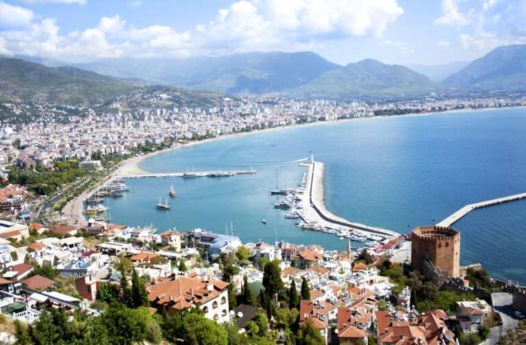 Urlaubsreisen Luftaufnahme des Hafens von Alanya mit Booten und der Küste im Hintergrund.