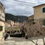 Malerische Gasse in Valldemossa, Mallorca, mit traditionellen Steinhäusern und bergiger Landschaft im Hintergrund