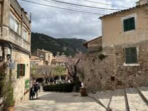 Malerische Gasse in Valldemossa, Mallorca, mit traditionellen Steinhäusern und bergiger Landschaft im Hintergrund