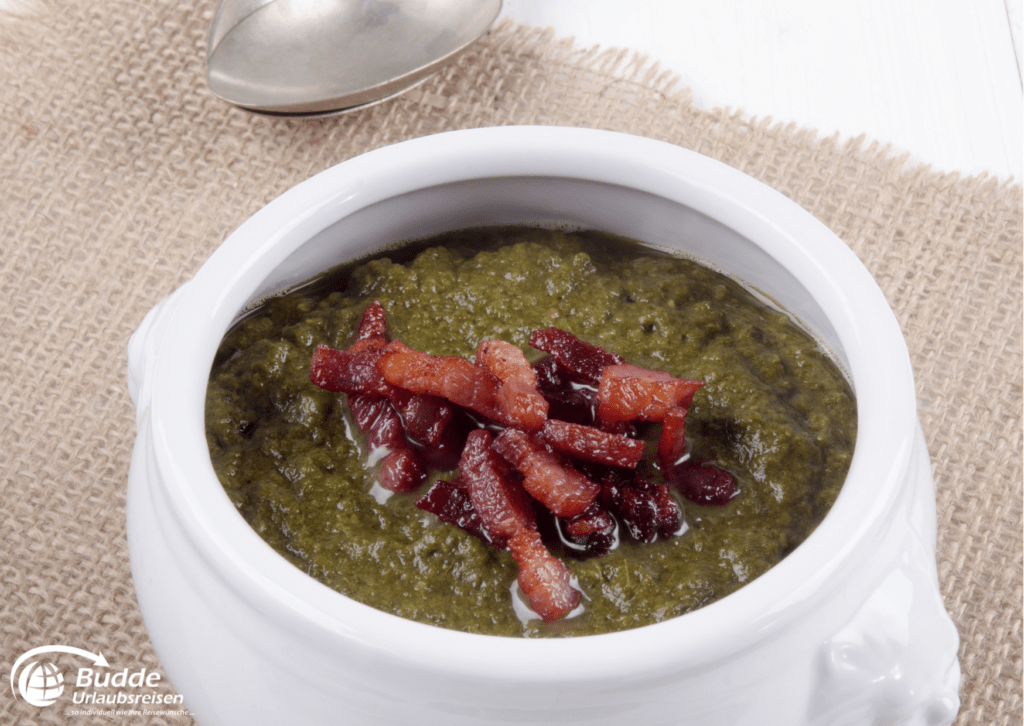 Eine Schüssel Callaloo Suppe mit Speckstücken garniert.