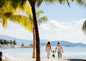 Familie spaziert Hand in Hand am Strand unter Palmen bei ihren Urlaubsreisen