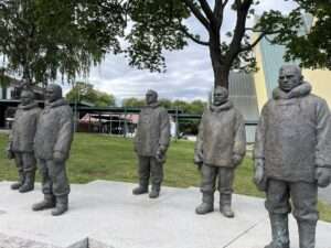 Skulpturen von fünf Männern in arktischer Kleidung im Freien.