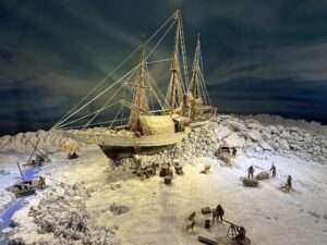 Modell eines Schiffs, das im Eis eingefroren ist, umgeben von Figuren und Ausrüstung.