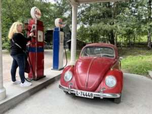 Anke Budde tankt ein rotes Auto an einer historischen Esso-Tankstelle.