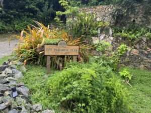 Ein Schild mit der Aufschrift "The Paradise Peak Boutique Hotel" umgeben von üppigem Grün in einem Adults-Only und LGBTQ-freundlichen Boutique-Hotel.