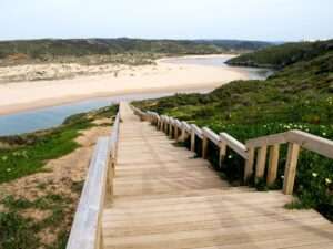 Holztreppe führt hinunter zu einem abgelegenen Strand an der Algarve-Küste.
