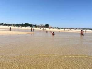 Sandstrand an der Algarve mit ruhigem Meer und weitläufigem Himmel.
