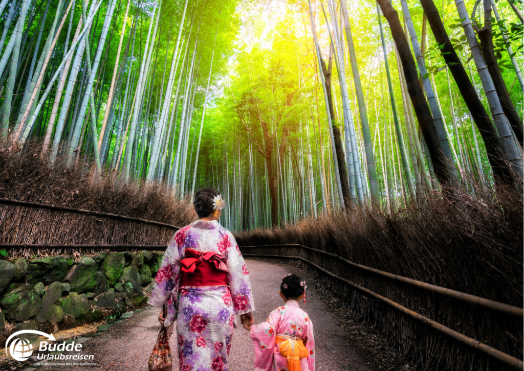 Eine Frau und ein Kind in traditionellen Kimonos spazieren durch einen Bambuswald. Nachhaltiges Reisen ist sollte für alle Reisenden eine wichtige Rolle haben.