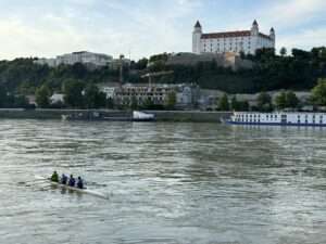 Ruderer auf der Donau vor der Burg Bratislava.