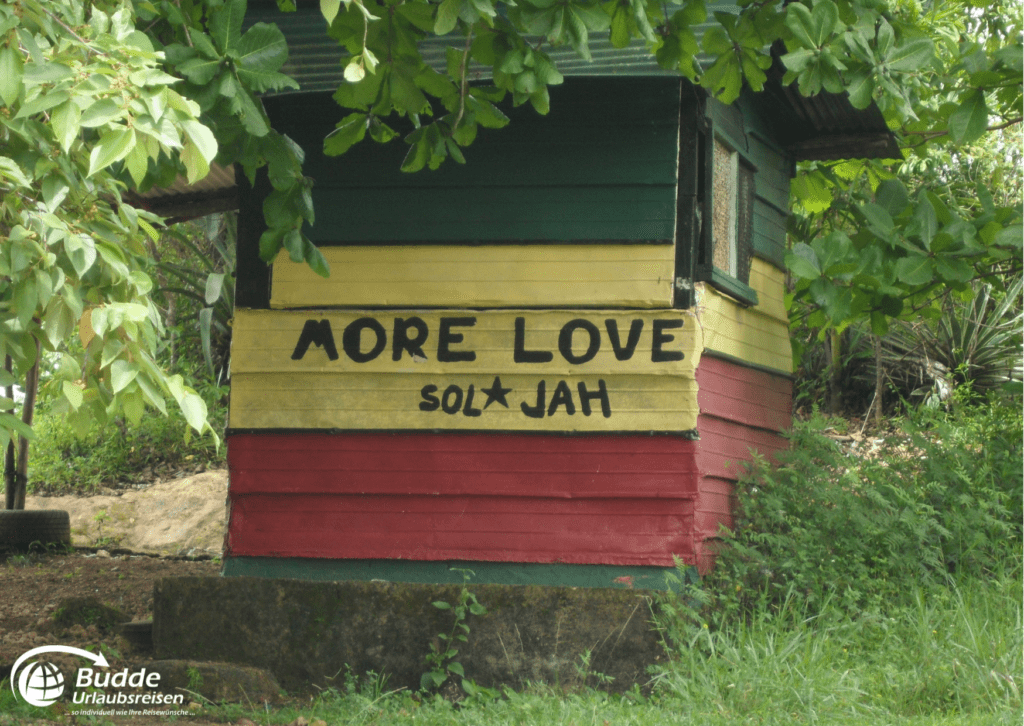 Holzhaus mit gelben, roten und grünen Streifen und dem Schriftzug 'MORE LOVE sol★JAH'.