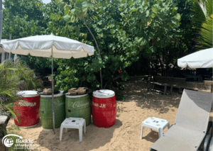 Pinel Island - Saint Martin: Strand mit Sonnenschirmen und Fässern