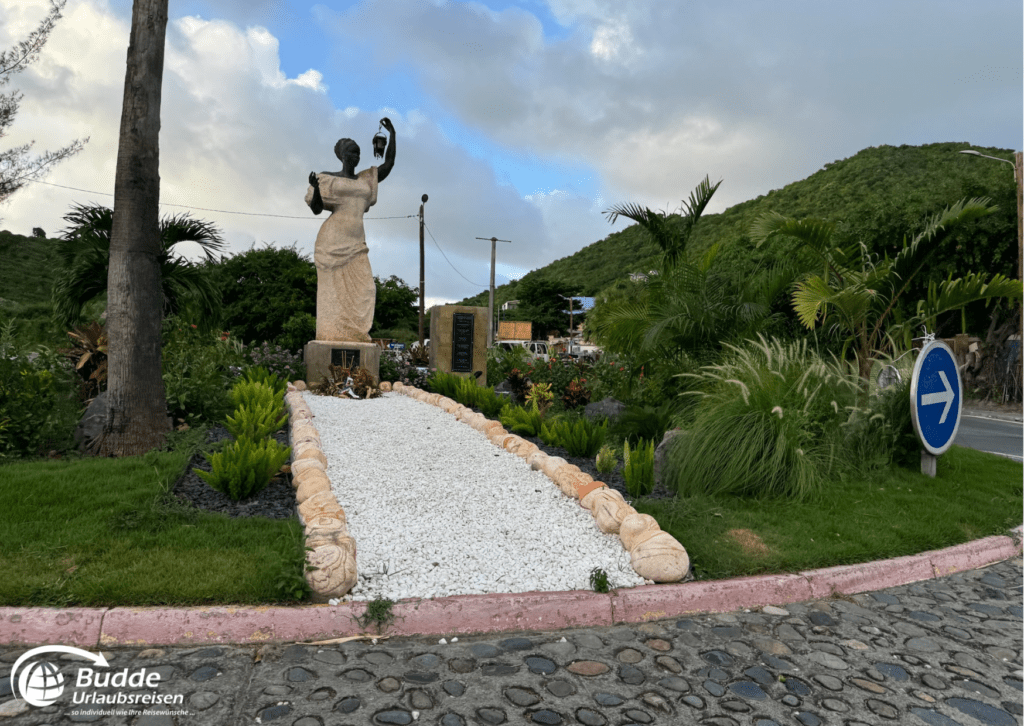 Reiseerfahrungen Saint Martin: Eine Statue in einem gepflegten Garten, angeboten von Budde Urlaubsreisen.