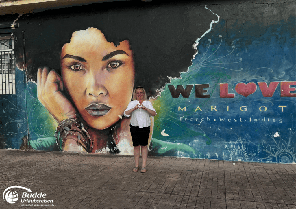 Ein weiteres Streetart-Wandgemälde in Marigot, Saint Martin, mit einer Frau, die ein Herzzeichen macht.
