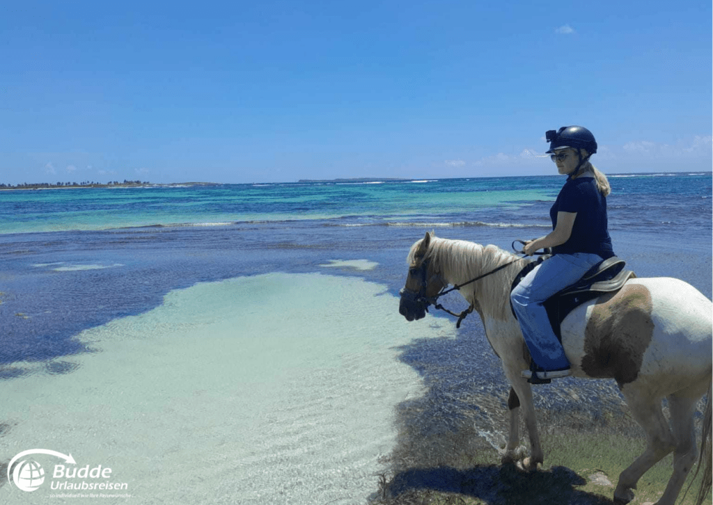 Eine Frau reitet am Strand von Sankt Martin entlang.