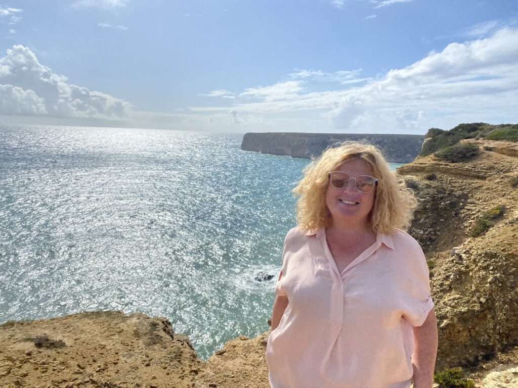 World Tourism Day 2024 - Frau steht an einer Klippe mit Blick auf das Meer an der Algarve, Portugal.