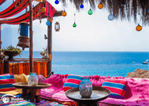 Ägypten Urlaub: Bunte Sitzgelegenheit mit Kissen und Gläsern, Blick auf das Meer im Hintergrund. - buchbar im Reisebüro Budde Urlaubseisen