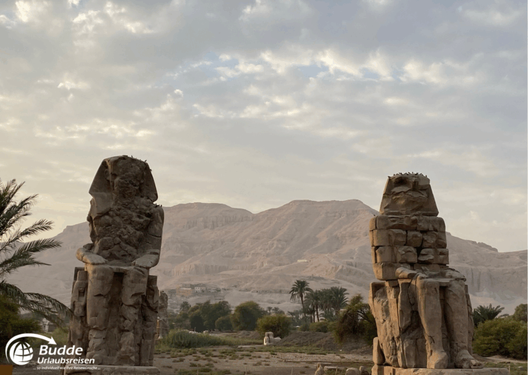 Ägypten Urlaub: Zwei große Statuen der Memnonkolosse in Luxor mit einer bergigen Landschaft im Hintergrund. - buchbar im Reisebüro Budde Urlaubseisen