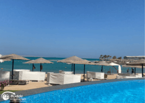 Ägypten Urlaub: Strand mit weißen Sonnenschirmen und Liegen am Wasser in Marsa Alam, Ägypten. - buchbar im Reisebüro Budde Urlaubseisen