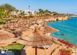 Ägypten Urlaub: Strandansicht mit Sonnenschirmen und Liegen am Wasser in Sharm el-Sheikh, Ägypten. - buchbar im Reisebüro Budde Urlaubseisen