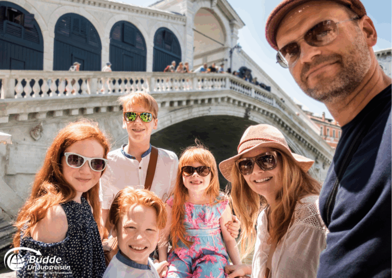 Langzeiturlaub buchen: Familienfoto mit sechs Personen, die Sonnenbrillen tragen, vor einer Brücke am Wasser. - buchbar im Reisebüro Budde Urlaubseisen