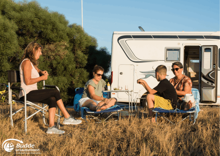 Langzeiturlaub buchen: Familie sitzt im Freien vor einem Wohnmobil und genießt die Zeit zusammen. - buchbar im Reisebüro Budde Urlaubseisen