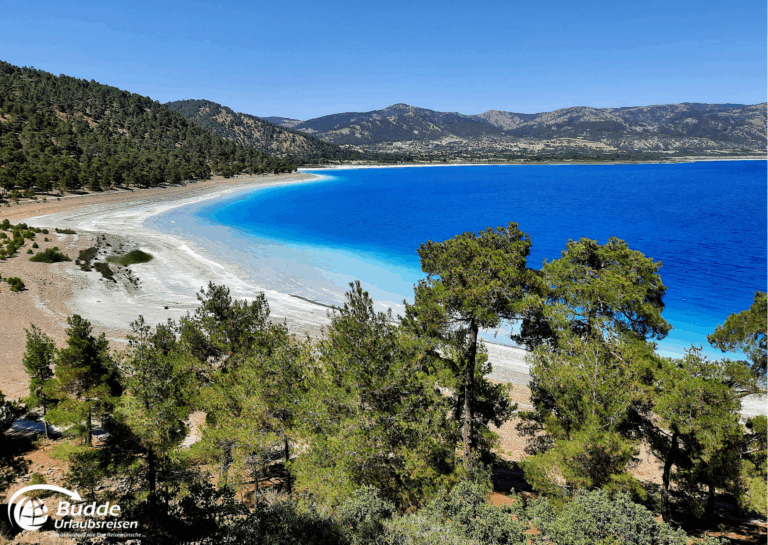 Langzeiturlaub buchen: Panoramablick auf einen Strand mit klarem Wasser und umgebenden Bäumen in der Türkei. - buchbar im Reisebüro Budde Urlaubseisen
