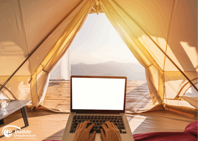 Langzeitreise buchen: Laptop auf einem Tisch im Inneren eines Zeltes mit Blick auf Berge und Himmel. - buchbar im Reisebüro Budde Urlaubseisen