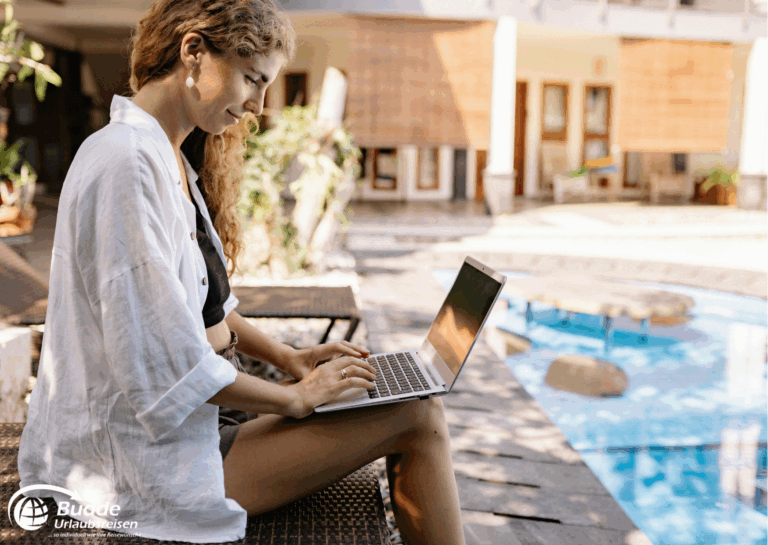 Langzeiturlaub buchen: Frau sitzt auf einer Liege und arbeitet an einem Laptop neben einem Pool. - buchbar im Reisebüro Budde Urlaubseisen