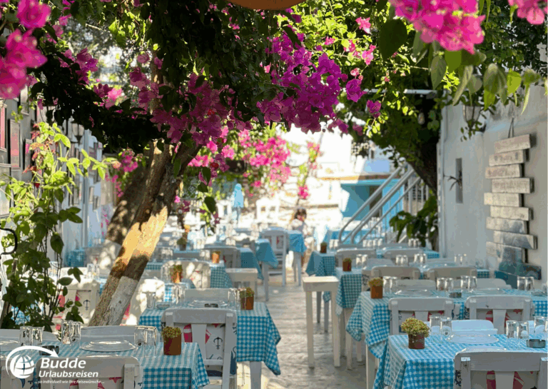 Langzeiturlaub buchen: Ein Restaurant mit weißen Tischen und blühenden Bougainvillea-Pflanzen in einer ruhigen Umgebung. - buchbar im Reisebüro Budde Urlaubseisen