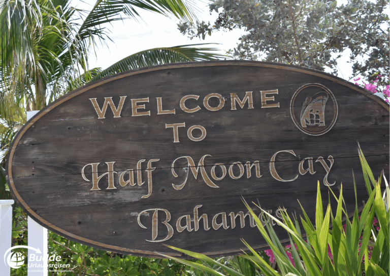 Holztafel mit der Aufschrift 'Willkommen zu Half Moon Cay, Bahamas' in goldenen Buchstaben. - Dein Luxusurlaub buchbar im Reisebüro Budde Urlaubseisen
