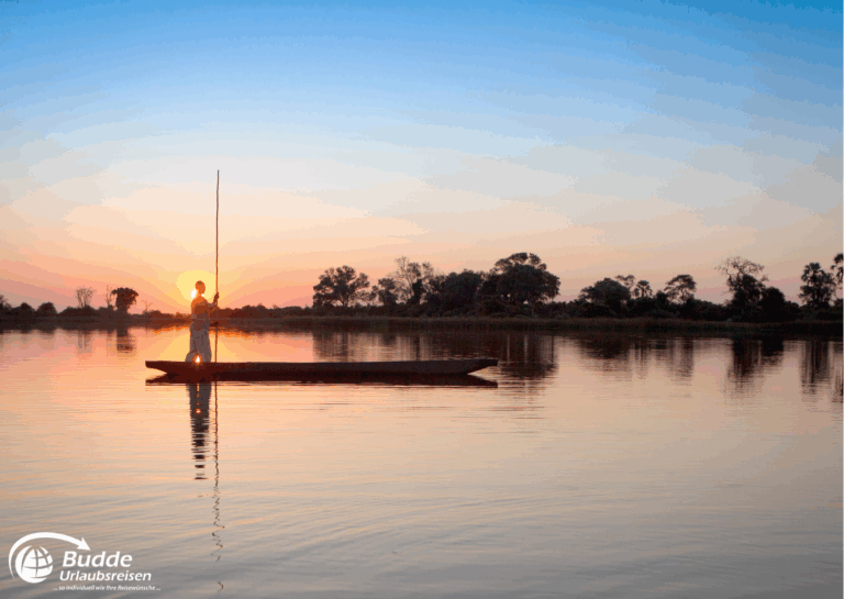 Mann steht auf einem Kanu im Okavango Delta bei Sonnenuntergang. - Dein Luxusurlaub buchbar im Reisebüro Budde Urlaubseisen
