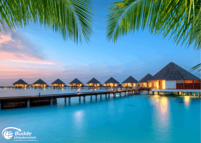 Wasserbungalows in den Malediven bei Sonnenuntergang mit ruhigem Wasser im Vordergrund. - buchbar im Reisebüro Budde Urlaubseisen
