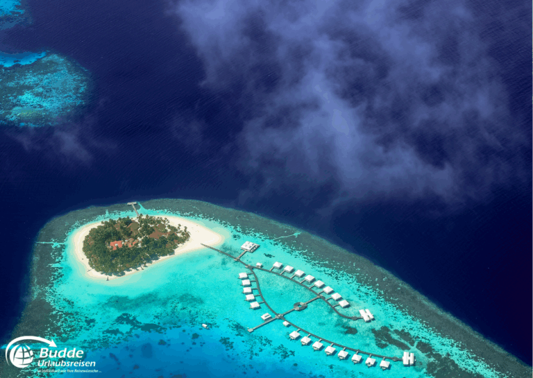 Luftaufnahme einer tropischen Insel mit Wasserbungalows und klarem blauen Wasser. - buchbar im Reisebüro Budde Urlaubseisen