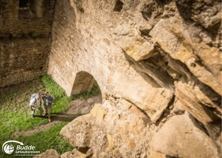 Urlaub an der Nahe: Zwei Personen erkunden die Ruine Disibodenberg in Bad Kreuznach, umgeben von alten Steinen. - buchbar im Reisebüro Budde Urlaubseisen