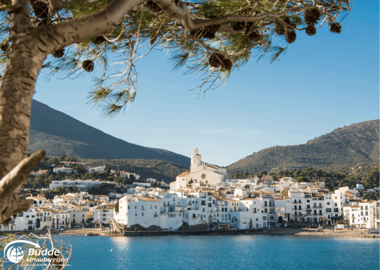 Mittelmeer per Schiff entdecken: Blick auf die Küstenstadt Cadaqués mit weißen Gebäuden und Bergen im Hintergrund. - buchbar im Reisebüro Budde Urlaubseisen