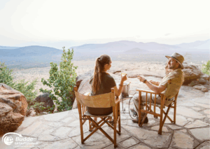 Romantikurlaub zu Zweit: Ein Paar sitzt auf einer Terrasse und genießt die Aussicht auf die Landschaft während des Sonnenuntergangs. - buchbar im Reisebüro Budde Urlaubseisen