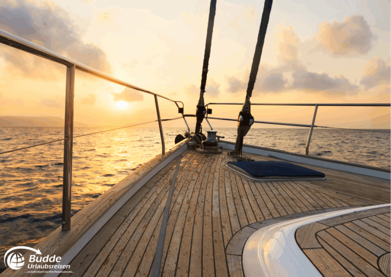 Romantikurlaub zu Zweit: Deck einer Segelyacht mit Holzoberfläche und Seeblick bei Sonnenuntergang. - buchbar im Reisebüro Budde Urlaubseisen