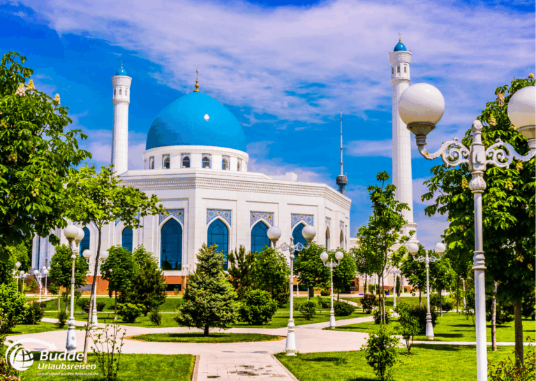 Rundreisen buchen: Moschee mit blauer Kuppel und weißen Säulen, umgeben von Bäumen und Laternen in Usbekistan. - buchbar im Reisebüro Budde Urlaubseisen