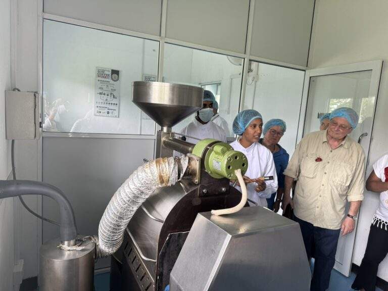 Kaffeeplantage in Kandy: Kaffeeröstmaschine mit mehreren Personen, die den Röstprozess beobachten. - buchbar im Reisebüro Budde Urlaubseisen